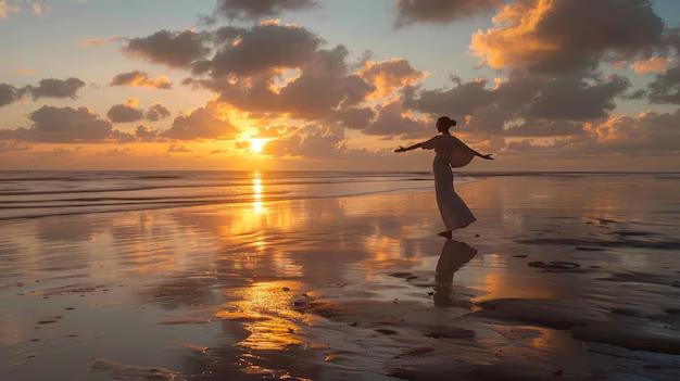 Woman with arms outstretched on the beach at sunset