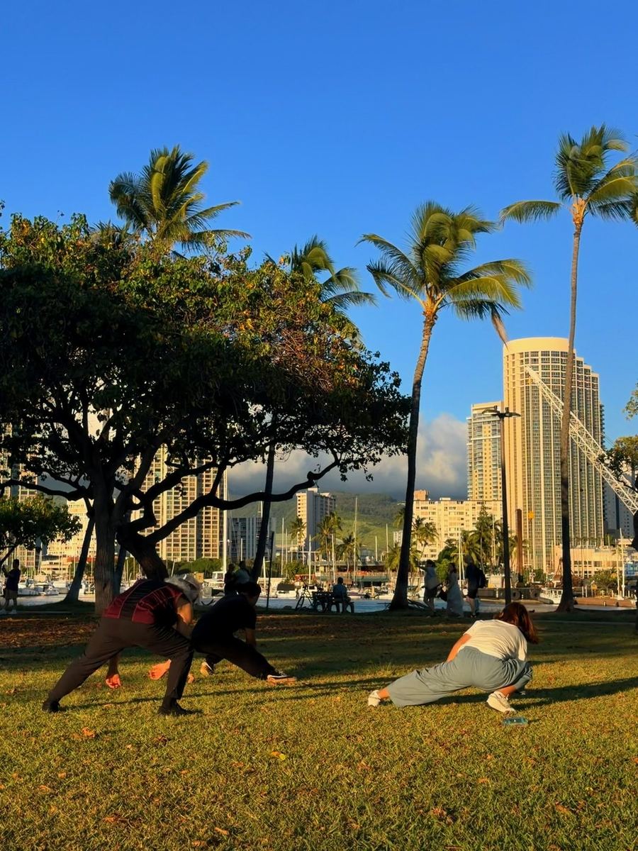 Group practicing Tai Chi outdoors near the Honolulu skyline